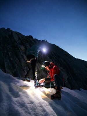 Two people on the side of a mountain with a light