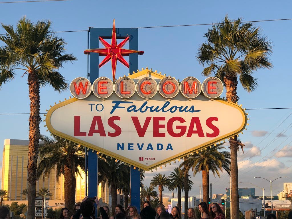 Famous Las Vegas Welcome sign surrounded by palm trees at sunset.