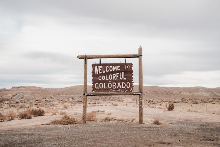 Desolate landscape in Colorado featuring a rustic welcome sign, ideal for travel themes.